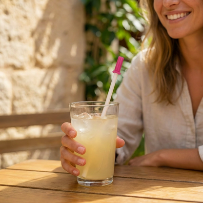 Strwky roze op een papieren rietje bij een drankje op een zonnig terras